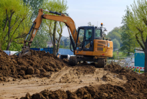 Orange excavator on caterpillar tracks moves earth on construction site